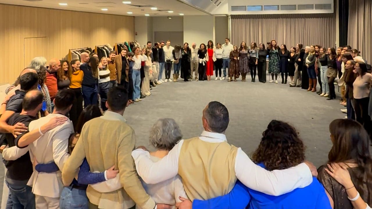 Une soixantaine de participants au séminaire Invincible, debout en cercle, bras dessus bras dessous